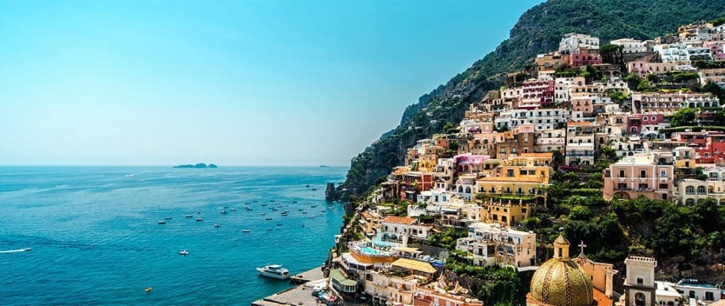 A breathtaking view of Positano, Italy, with its colorful cliffside buildings cascading down to the sparkling blue sea, epitomizing the charm and allure of the Amalfi Coast.