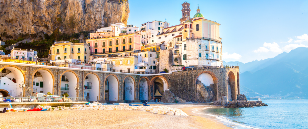 Atrani Beach, a picturesque and secluded coastal spot nestled between towering cliffs, featuring crystal-clear turquoise waters and colorful umbrellas, offering a peaceful and scenic escape in Atrani, Italy.