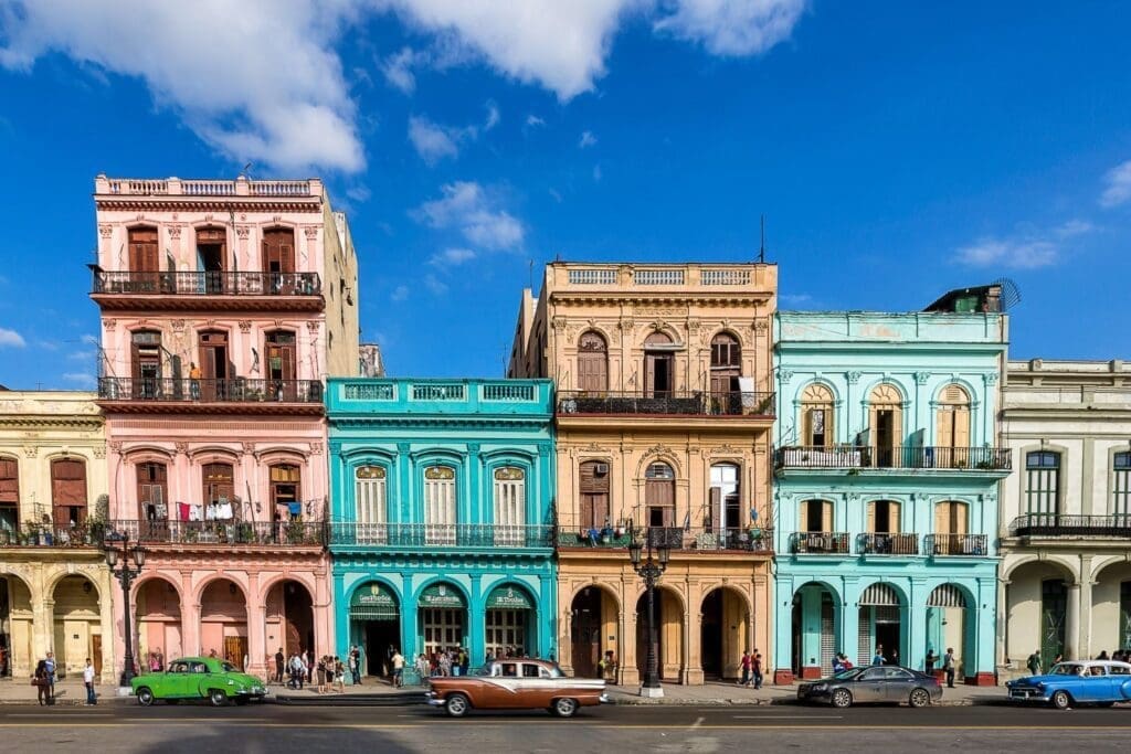 The main street in Havana with old restored facades of buildings and vintage cars on the street.