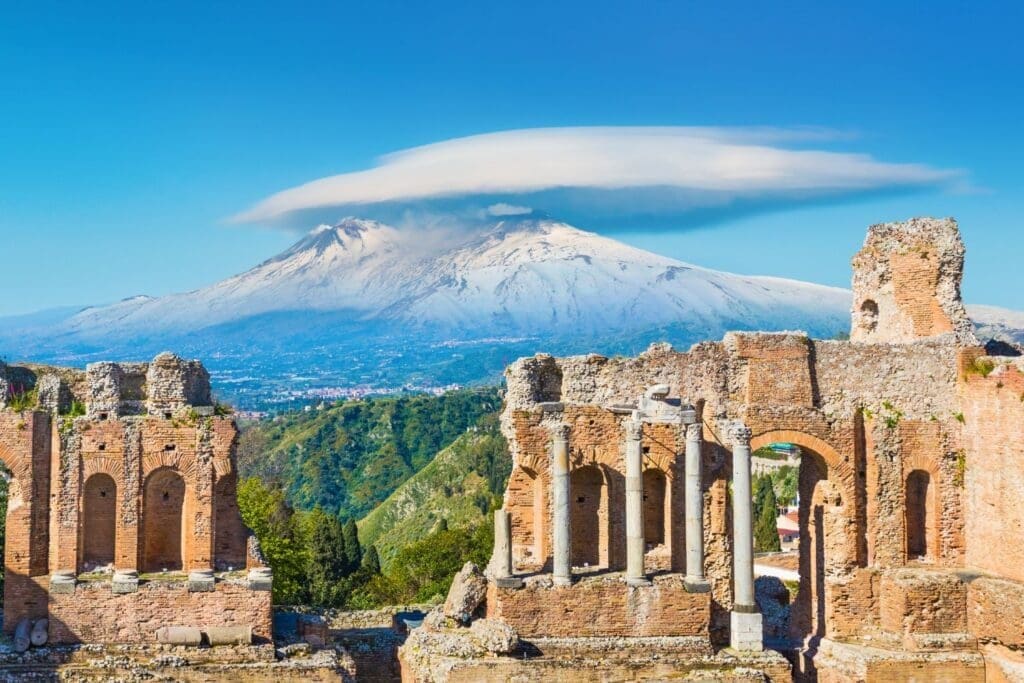 Ancient Greek theatre in Taormina on background of Etna Volcano
